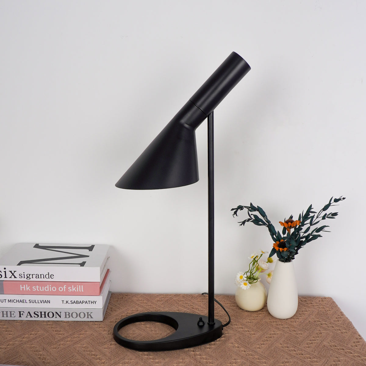 Onyx-black cylindrical lamp creating pool of light on wooden desk surface