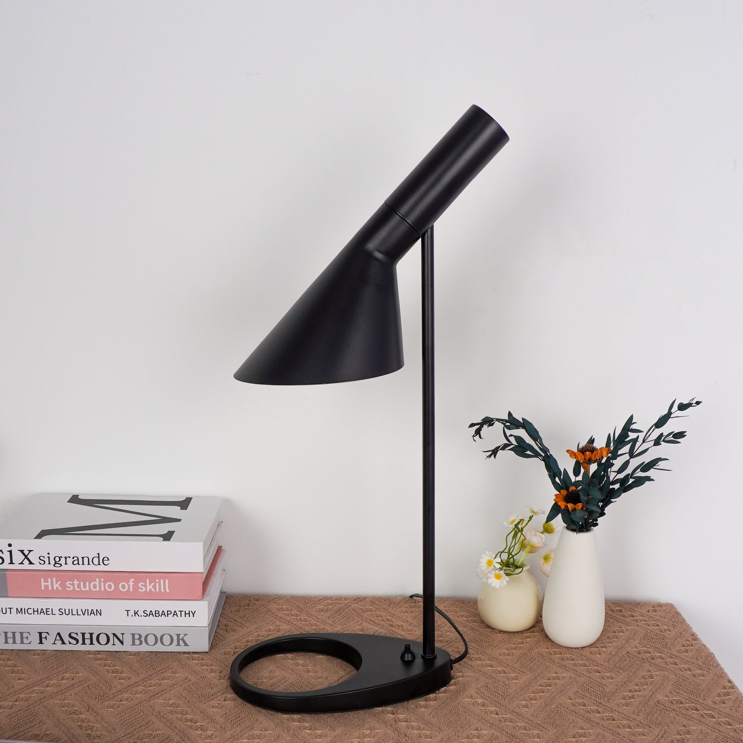 Onyx-black cylindrical lamp creating pool of light on wooden desk surface