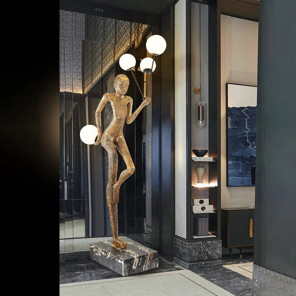 At the entrance of the hall, a golden human sculpture floor lamp stands, with bright spherical lights.