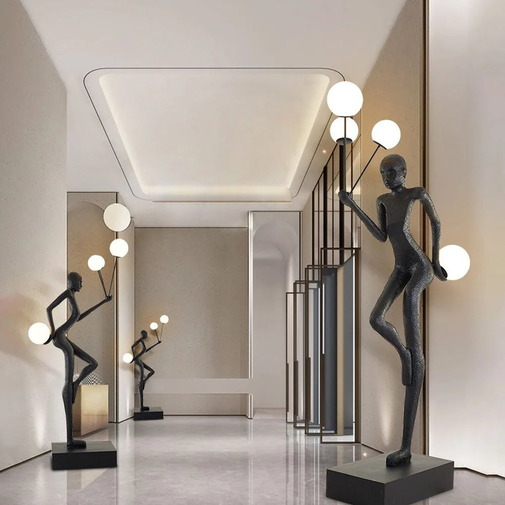 In the corridor, several black human-shaped floor lamps are placed in a staggered manner, and the spherical lampshades on the lamps emit bright white light.