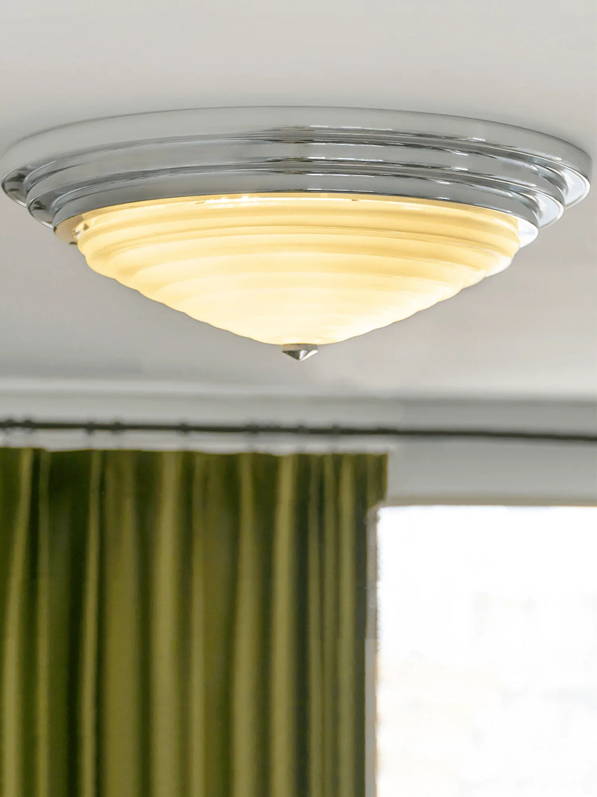 The white acrylic shade of the American Circle Ceiling Light emits a warm glow.