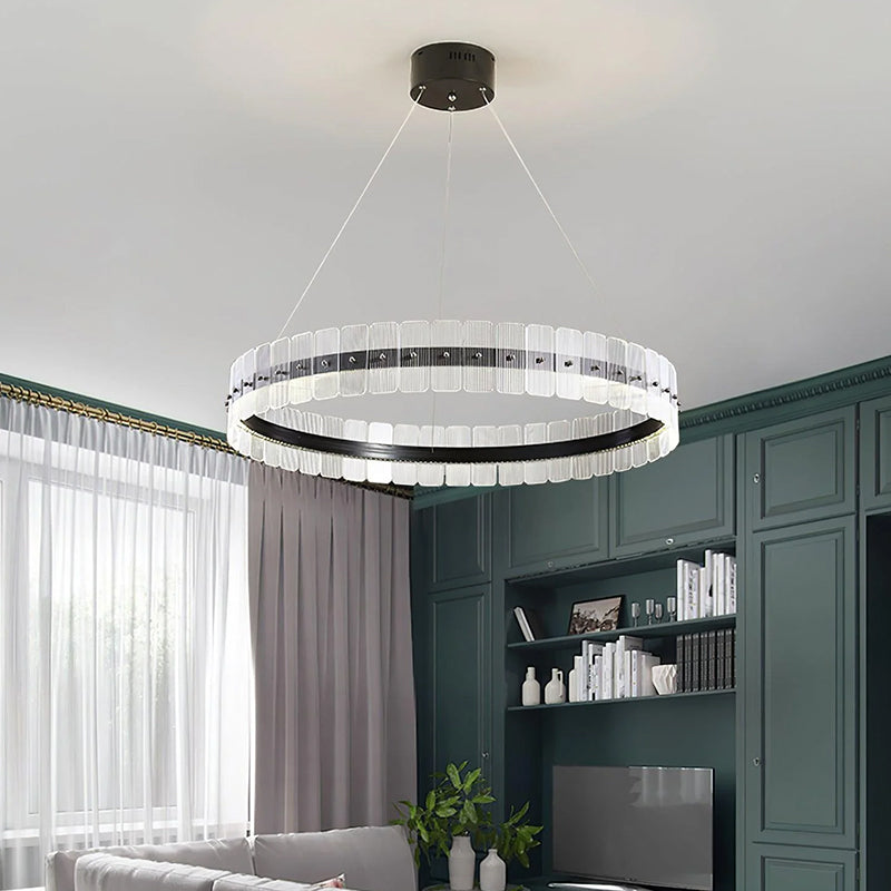 In this living room, a circular chandelier hangs lightly from the ceiling, with the clean lines of black metal interweaving with the clear acrylic material.