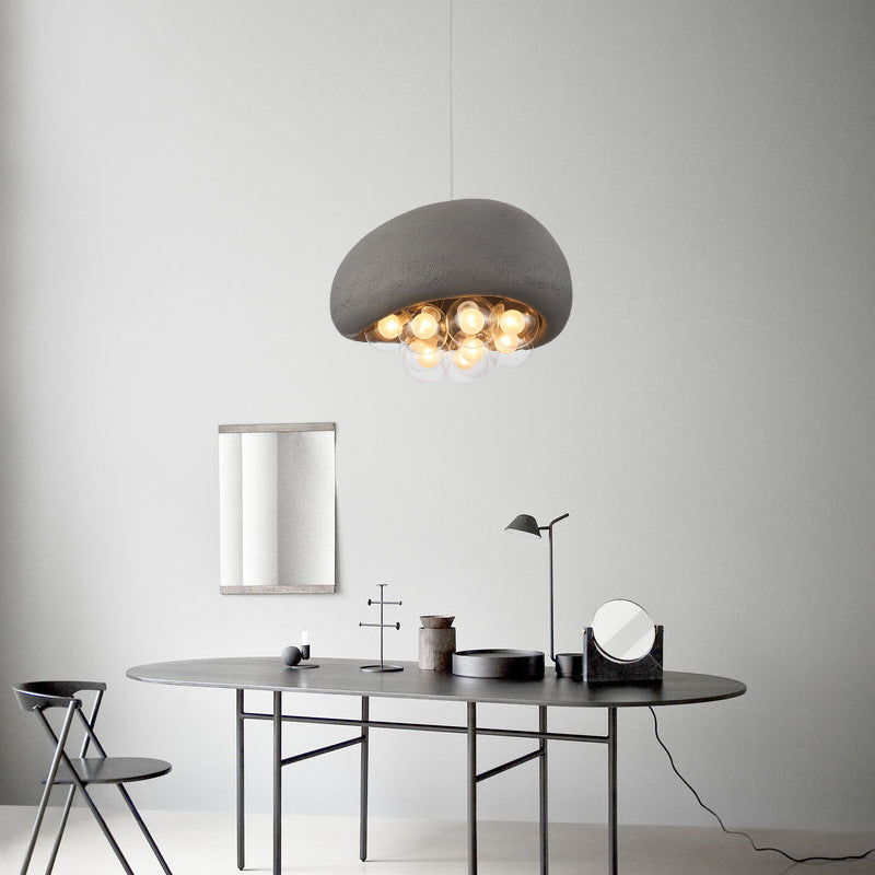 Cement - toned pendant lamp with mushroom - like shade and transparent bubble - orbs holding bulbs, adding modern art.