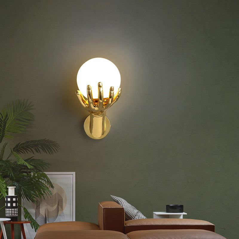 The golden hand-shaped wall lamp emits soft light and decorates a stylish room