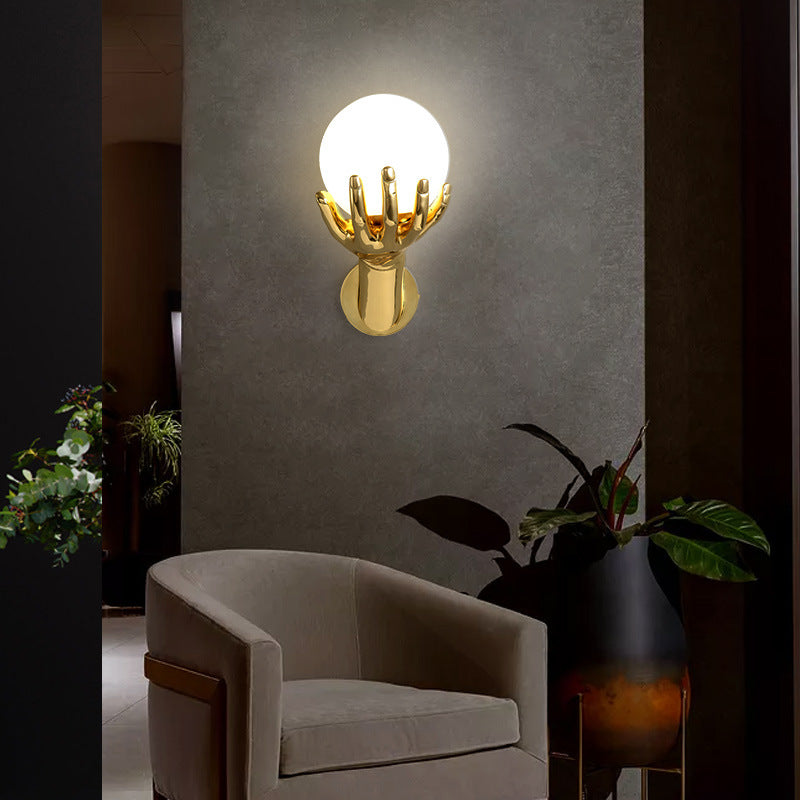 The golden hand-shaped wall lamp on the wall emits soft light, matched with beige seats.