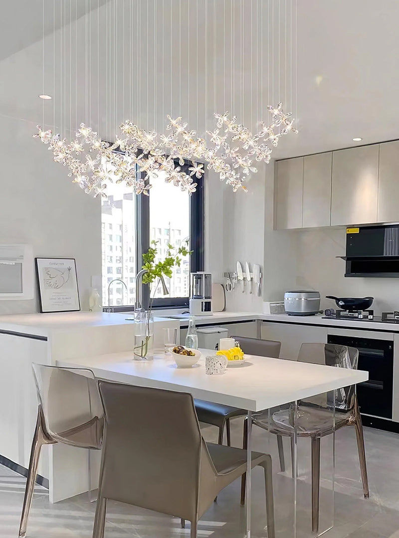 A chandelier made of multiple crystal flowers hangs over the modern kitchen