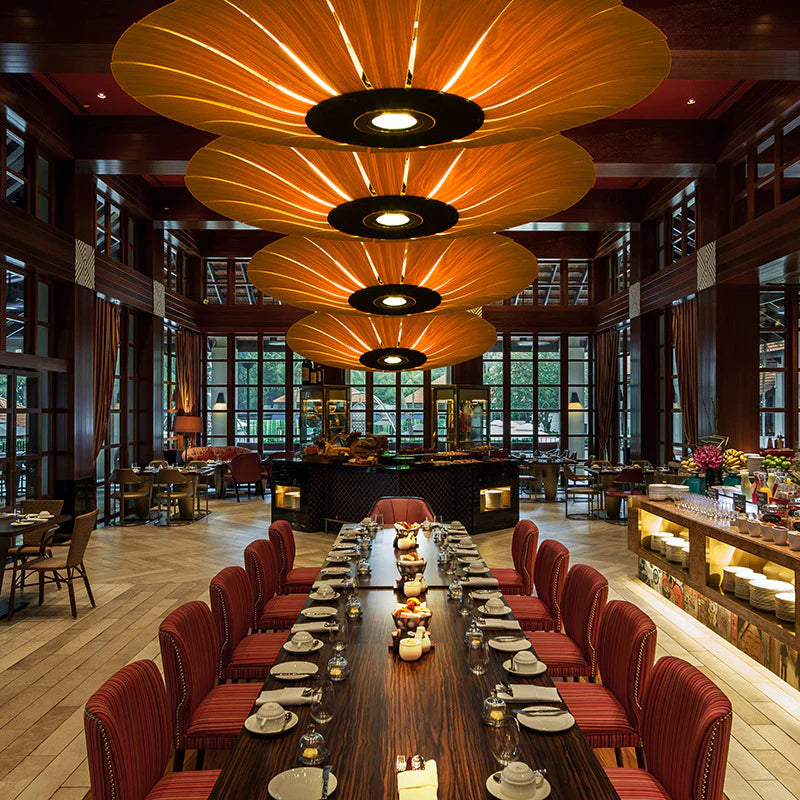 In the restaurant, a set of natural wood ceiling lamps shaped like blooming flowers hang above the long dining table.