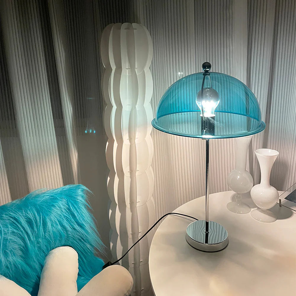 The Edinburgh Table Lamp with a blue translucent acrylic shade illuminates the reading area.