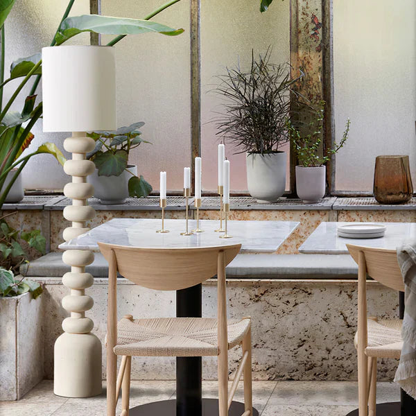The lamp’s resin base (artful tiers) + fabric shade filter light, tying the room’s modern and cozy elements together.