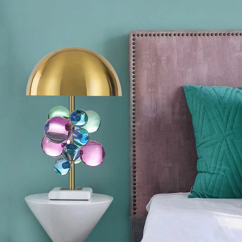 With a glossy golden top, vibrant glass orbs, and a marble stand, it’s a striking bedroom piece.