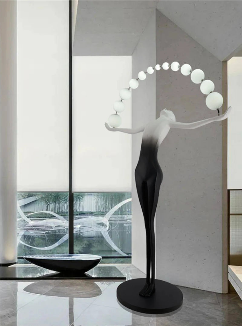 The human-shaped floor lamp stretching and performing is in the corner of the hotel lobby, as if welcoming guests.
