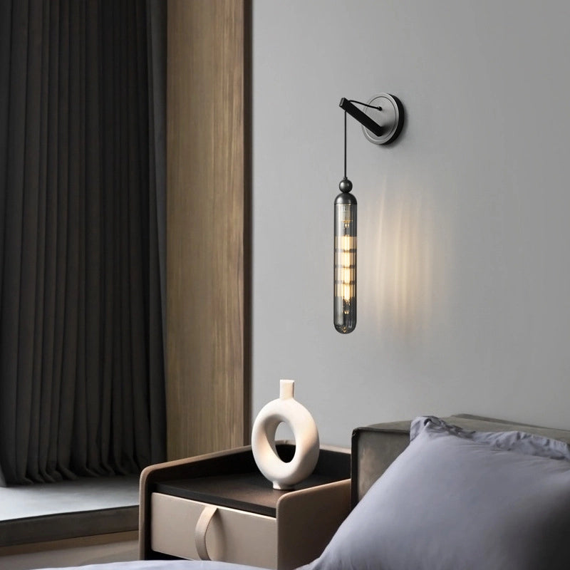 In a corner of a modern bedroom_a simplewall lamp is hung on the light gray wall.The black metal parts are matched with transparent lamp tubes_and the warm light is lightly sprinkled.