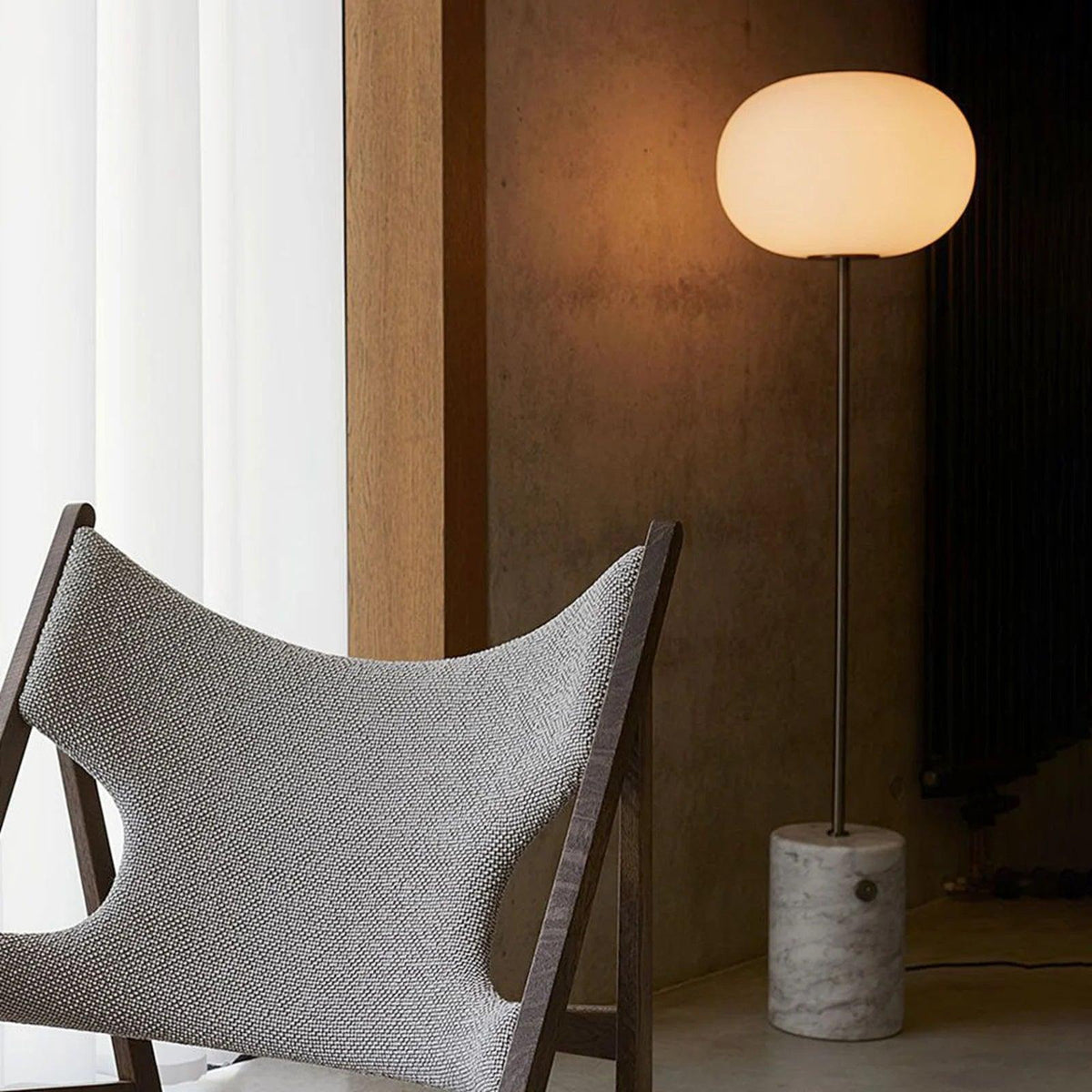 The Jwda Glass Floor Lamp with a white glass spherical lampshade on top emits a faint warm light