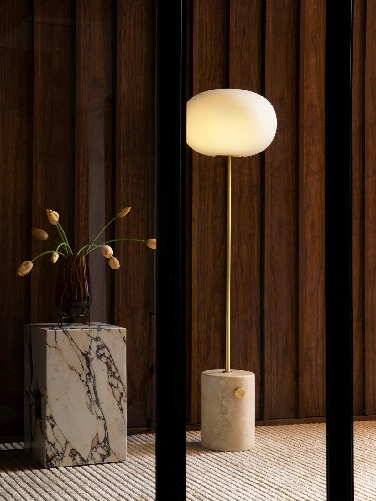 The glowing Jwda Glass Floor Lamp and marble potted plants decorate the corridor