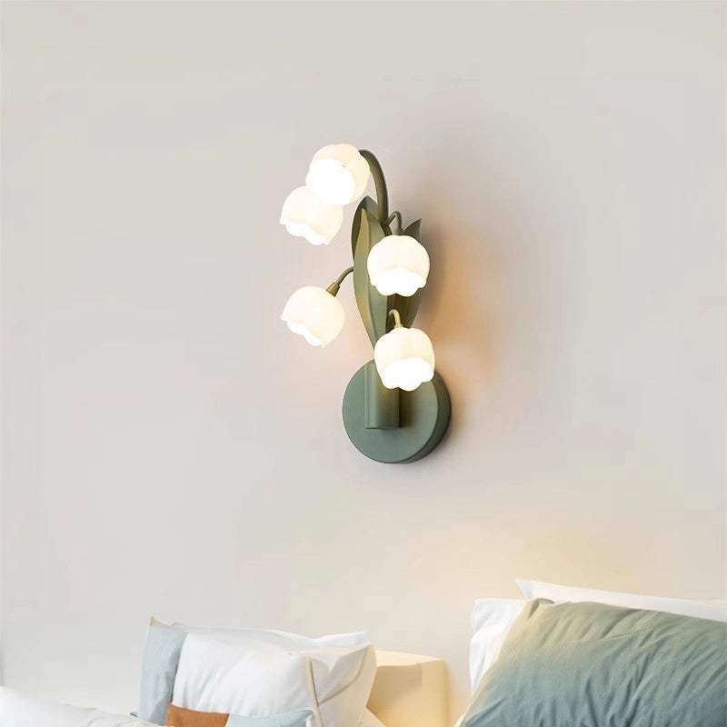 In the simple bedroom, the dark green wall lamp is like an elegant lily of the valley branch, and the five white lampshades are like blooming flowers, casting soft light.