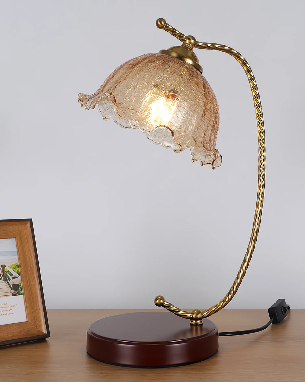The amber glass bud-shaped table lamp sits on the table, with a photo frame placed beside it.
