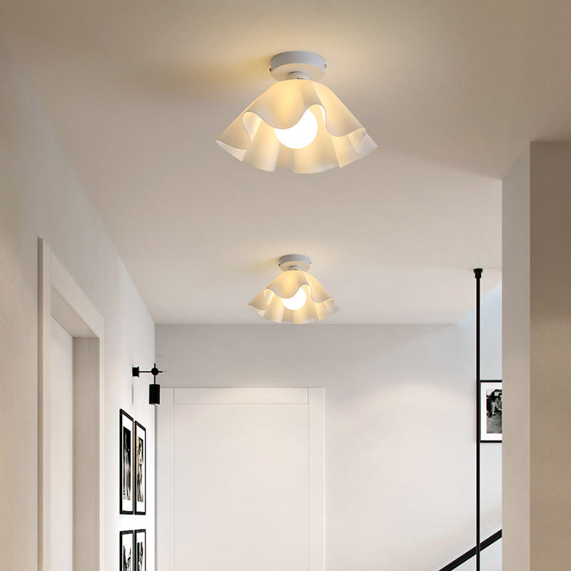 On the white ceiling of the corridor, two petal-shaped ceiling lights are arranged in sequence, with soft warm light.