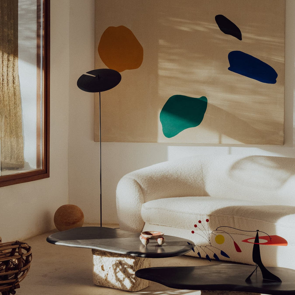 A floor lamp with a dark brown circular shade and slim metal stand, adding artistic charm to the space.