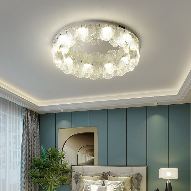 The Round Shell Ceiling Light emits a cool white light in the light-colored bedroom.