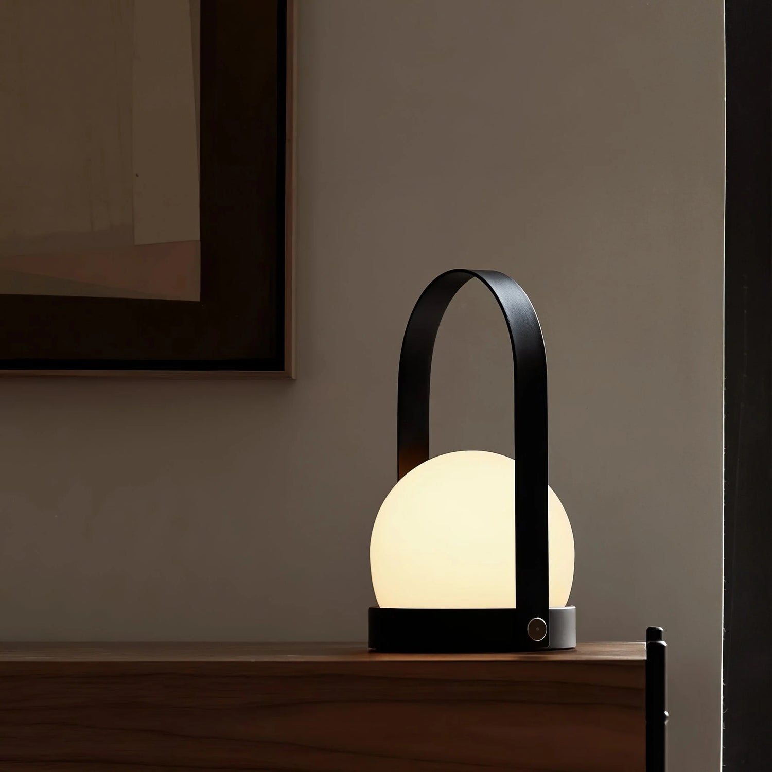 This table lamp features a sleek arched handle, blending seamlessly with its rounded lampshade to deliver soft, warm light.