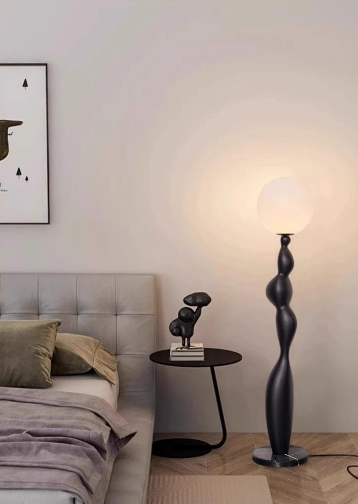 The black Very Sense Floor Lamp illuminates the cozy bedroom