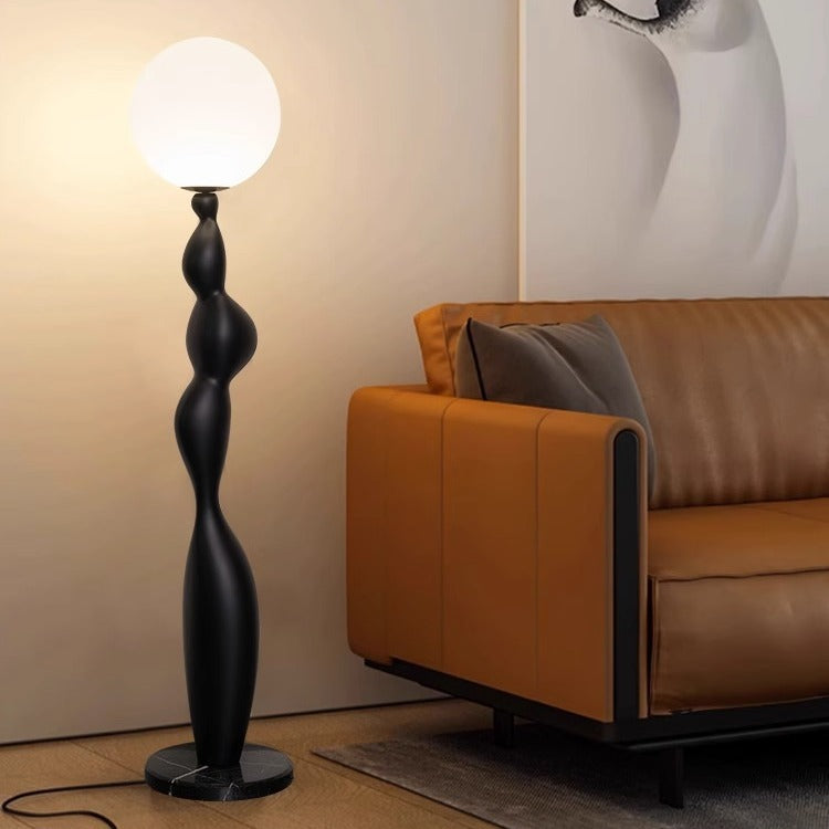 At night, the black Very Sense Floor Lamp next to the orange sofa emits a cozy warm light.