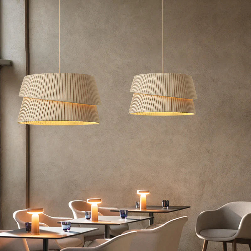 In the restaurant, several fabric chandeliers hang in front of the rough grey wall.