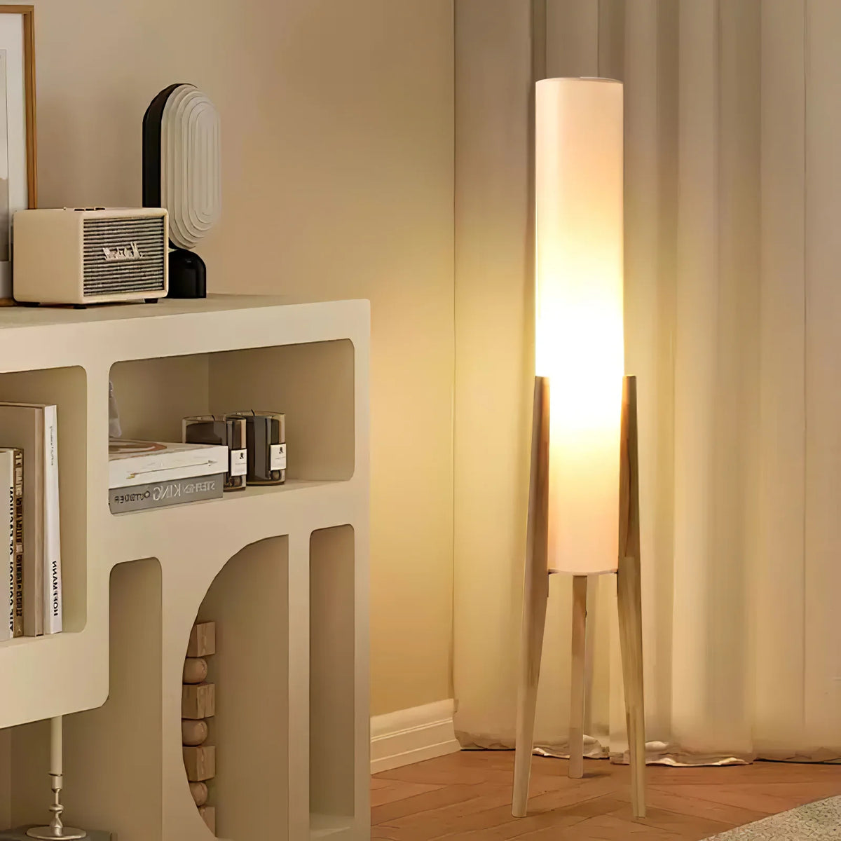 In a corner of the room, a three-legged floor lamp on a shelf emits soft warm light.