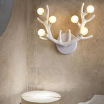 White resin antler wall sconce casting upward ambient light in a modern Scandinavian living room.