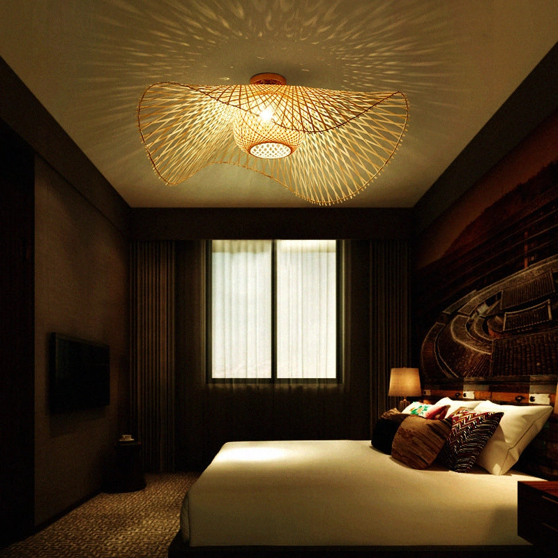 Bamboo Wave Ceiling Lamp: Woven bamboo light (curved design) casting warm patterns in a cozy hotel bedroom.