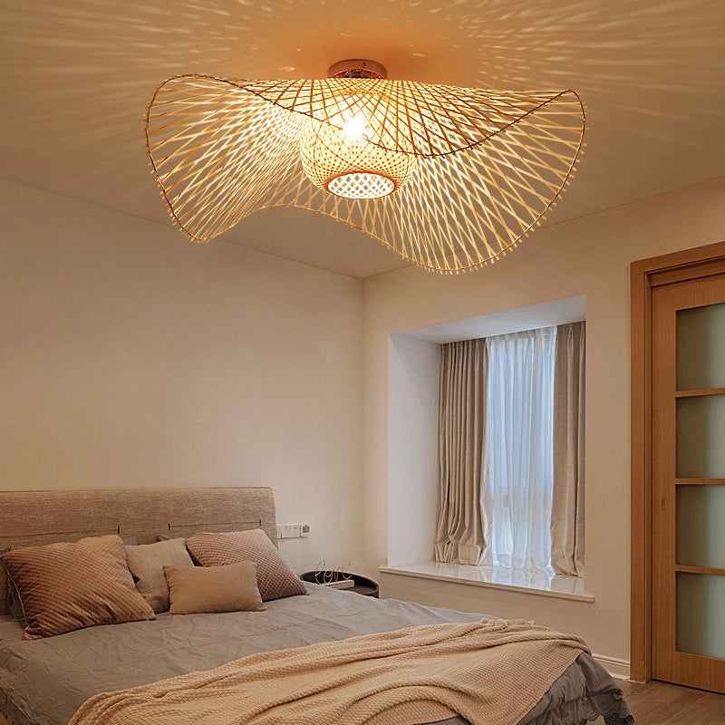 Woven bamboo light with curved design, casts warm patterns in bedroom.