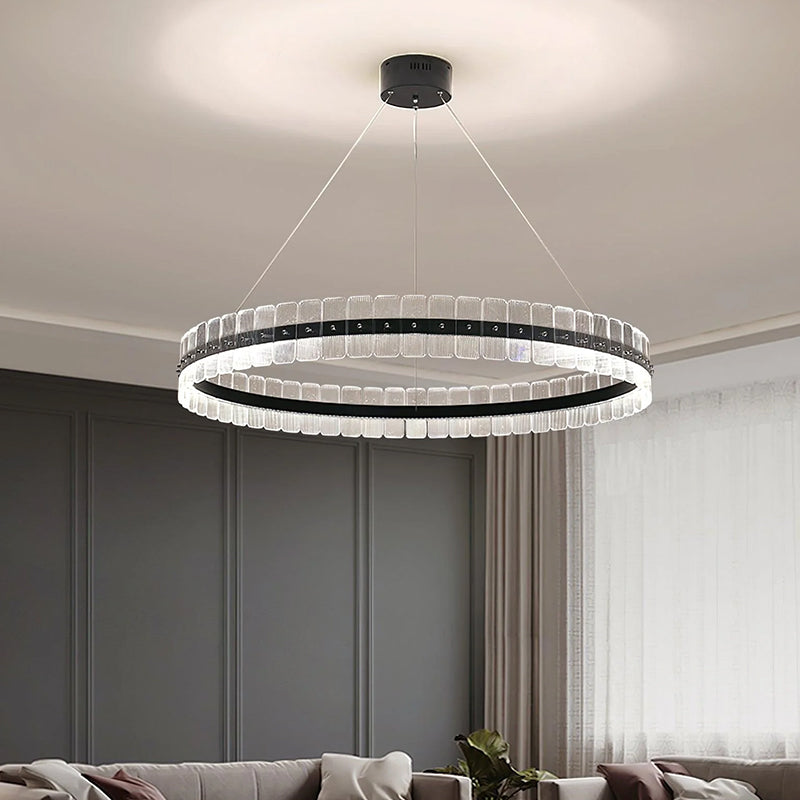 In the living room, a circular chandelier hangs elegantly from the ceiling, with a black metal frame and clear acrylic material.