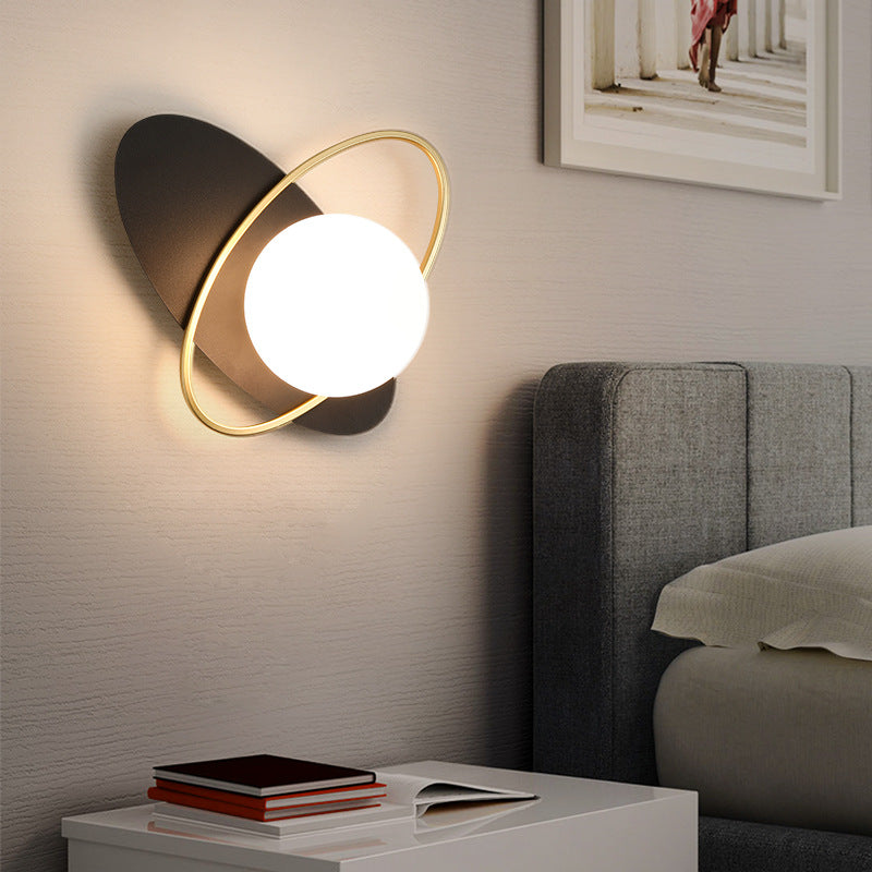 A Galaxy Wall Lamp with a white glass ball shade and a golden ring around it.