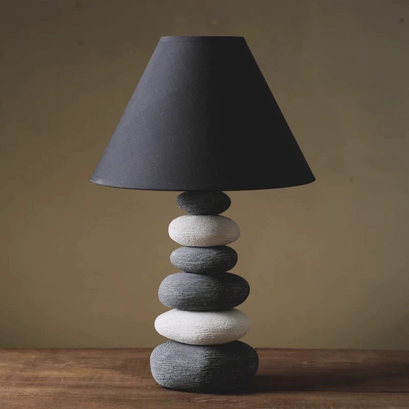 Artisanal ceramic lamp with organic stone-inspired details and a soft-hued linen shade.