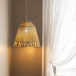 Handmade tassel lamp emits warm light next to the curtains