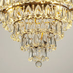 Close‑up view of grape crystal chandelier, glowing teardrop crystal pendants and vintage carved metal trim under warm‑toned light