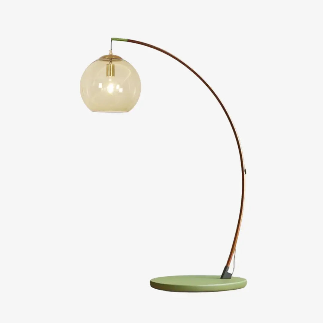 Contemporary Arc Floor Lamp with Glass Shade, curved walnut wood arm, green round metal base and amber glass globe shade on plain white background