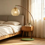 Contemporary Arc Floor Lamp with Glass Shade glowing warm light beside wooden bedside cabinet for bedroom floor lighting