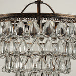 Detail shot of unlit teardrop crystal ornaments for tiered grape chandelier, clear faceted glass and antique metal frame decoration