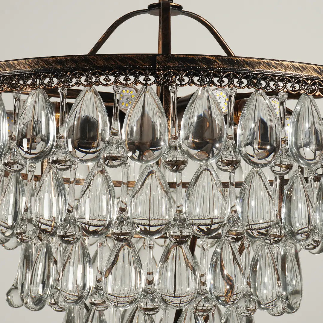 Detail shot of unlit teardrop crystal ornaments for tiered grape chandelier, clear faceted glass and antique metal frame decoration