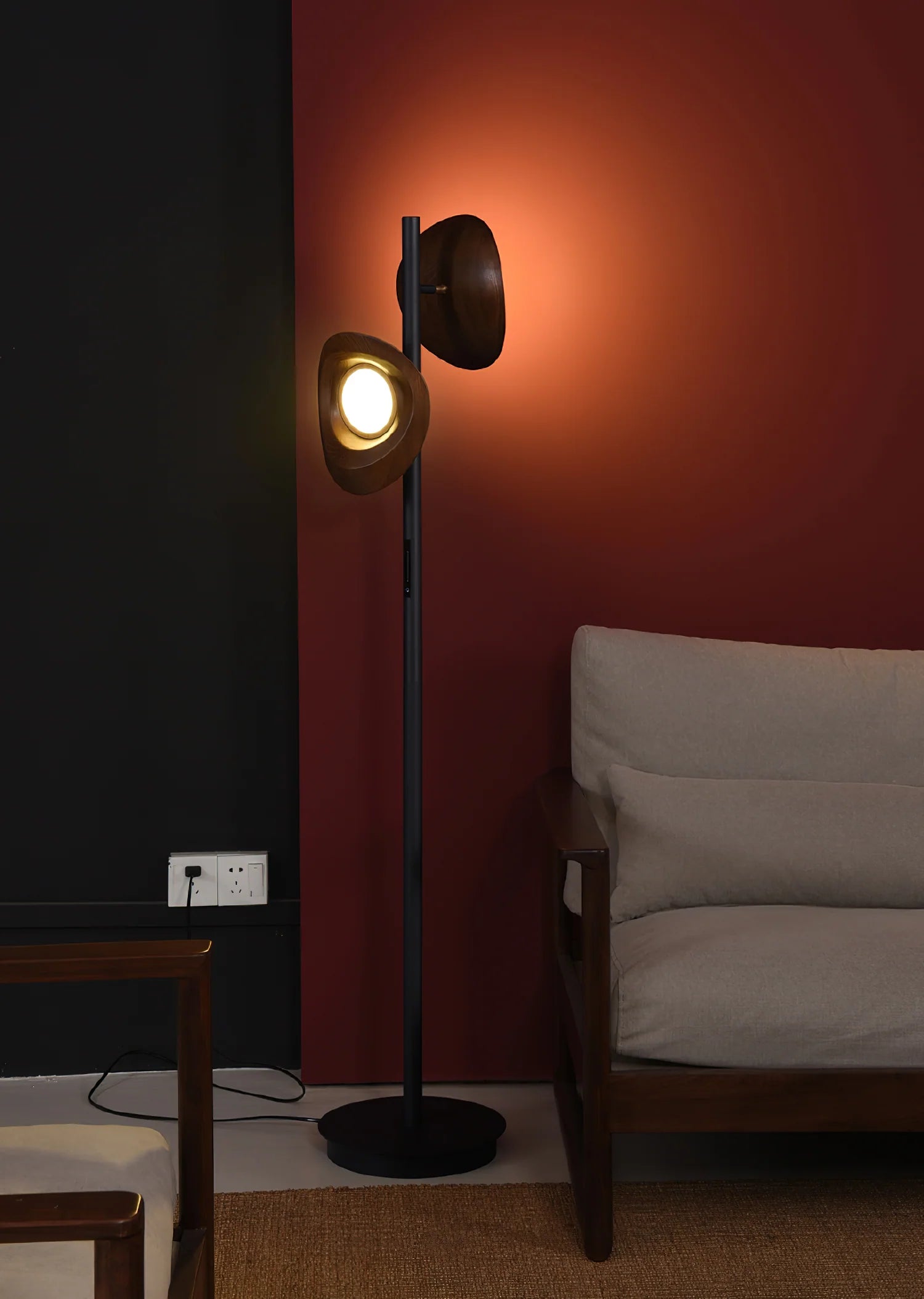 The floor lamp with a black base and two walnut lampshades is placed in the living room