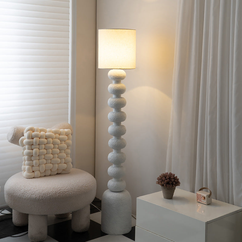 Emil Minimalist Floor Lamp with textured white base stands beside boucle chair in cozy neutral living room