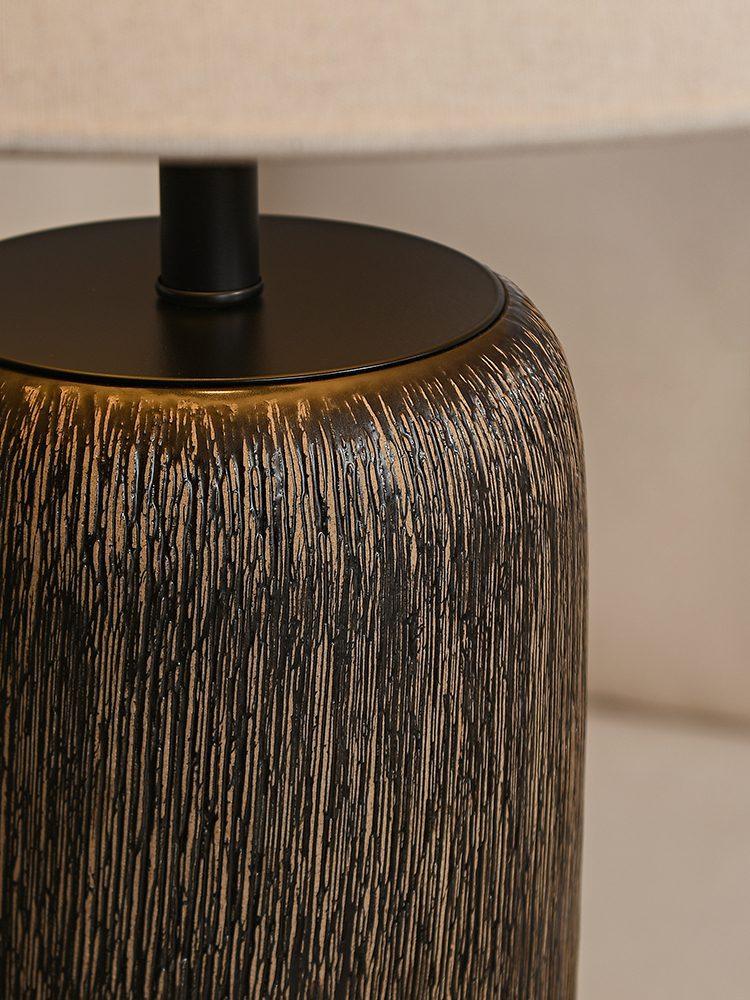 The junction between the top of the fabric lampshade and the lamp pole.