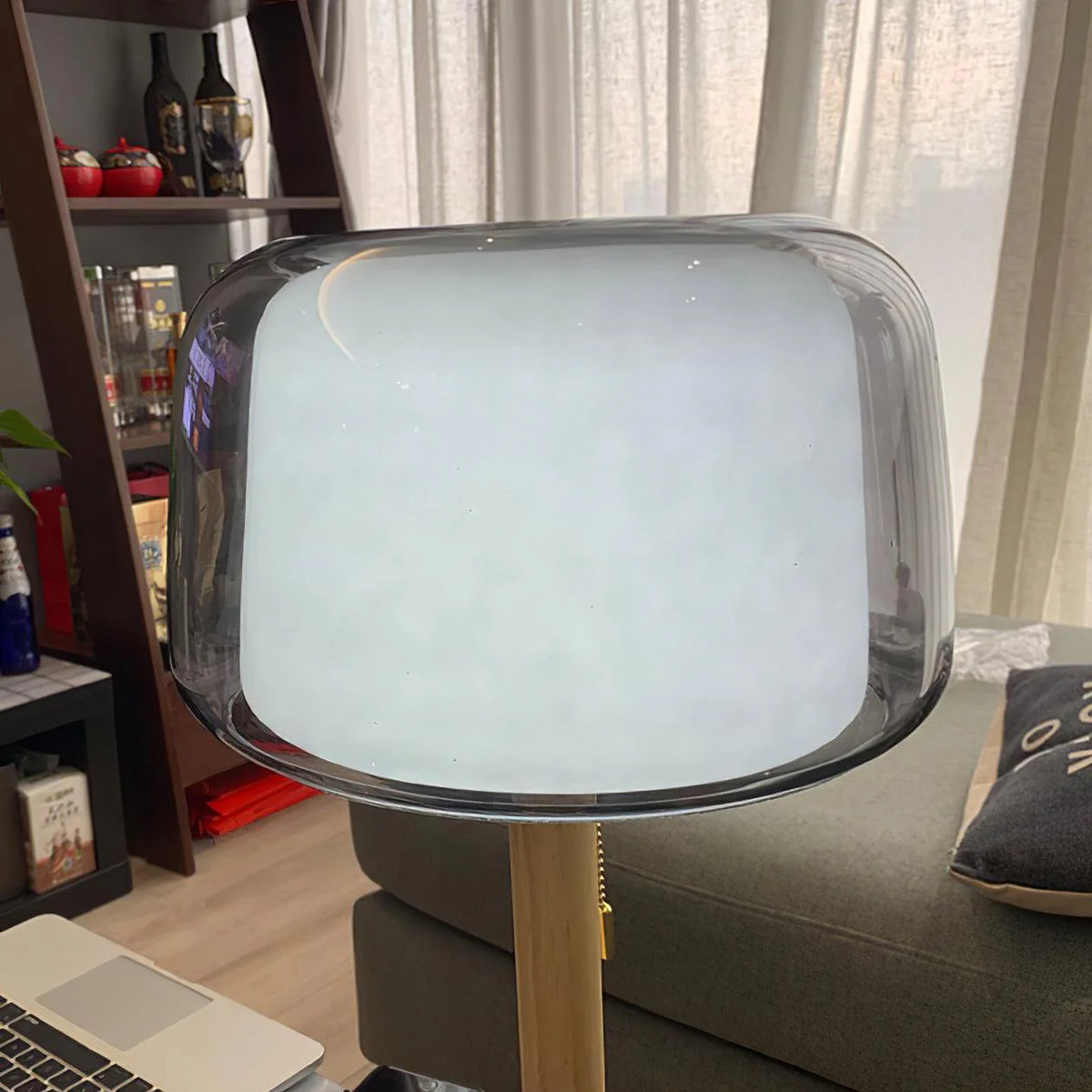 Close-up of a high-quality desk lamp with a smoky grey shade next to a computer