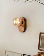 Artistic wall lighting: wooden base holds a textured glass sphere, casting gentle light to enhance your space.