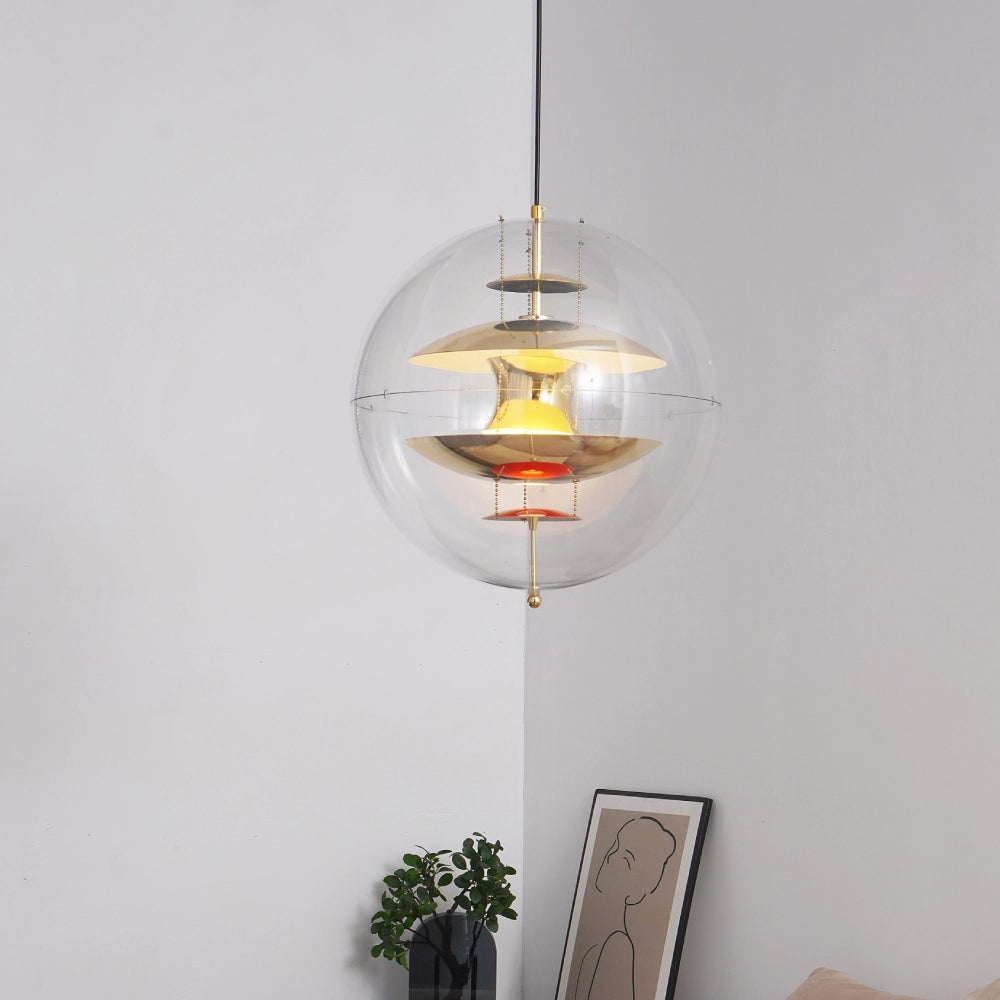 Modern pendant light with glass shade and gold accents on a neutral wall.