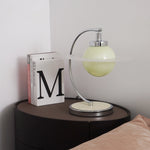 Planet-inspired table lamp with translucent green glass sphere and circular disc, modern bedside light with chrome frame