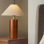 A bamboo wooden table lamp brights on a table next to the bed