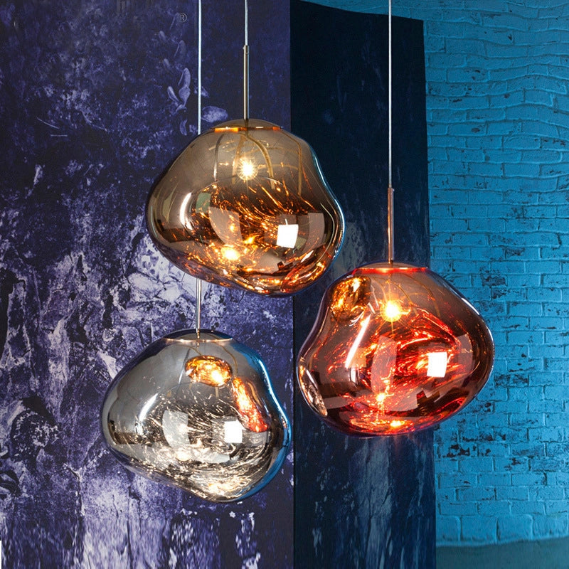 Three different colored lava-shaped pendant lights in a dark toned hallway