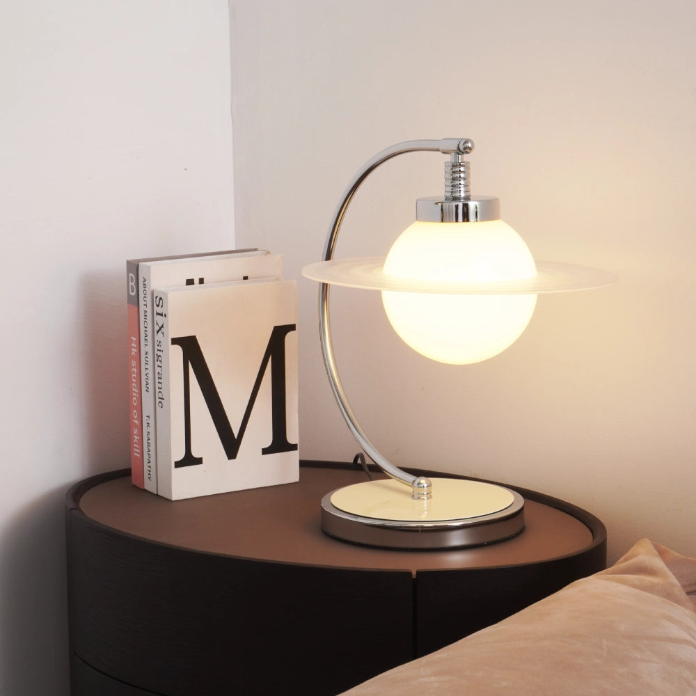 Planet style table lamp with glass shade on bedside table, modern desk lamp with warm ambient glow and curved metal frame